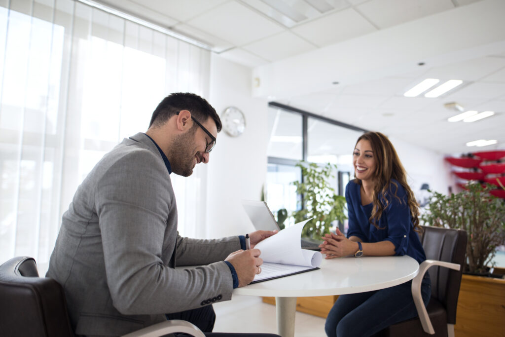Man interviewing a woman, writing on a notepad