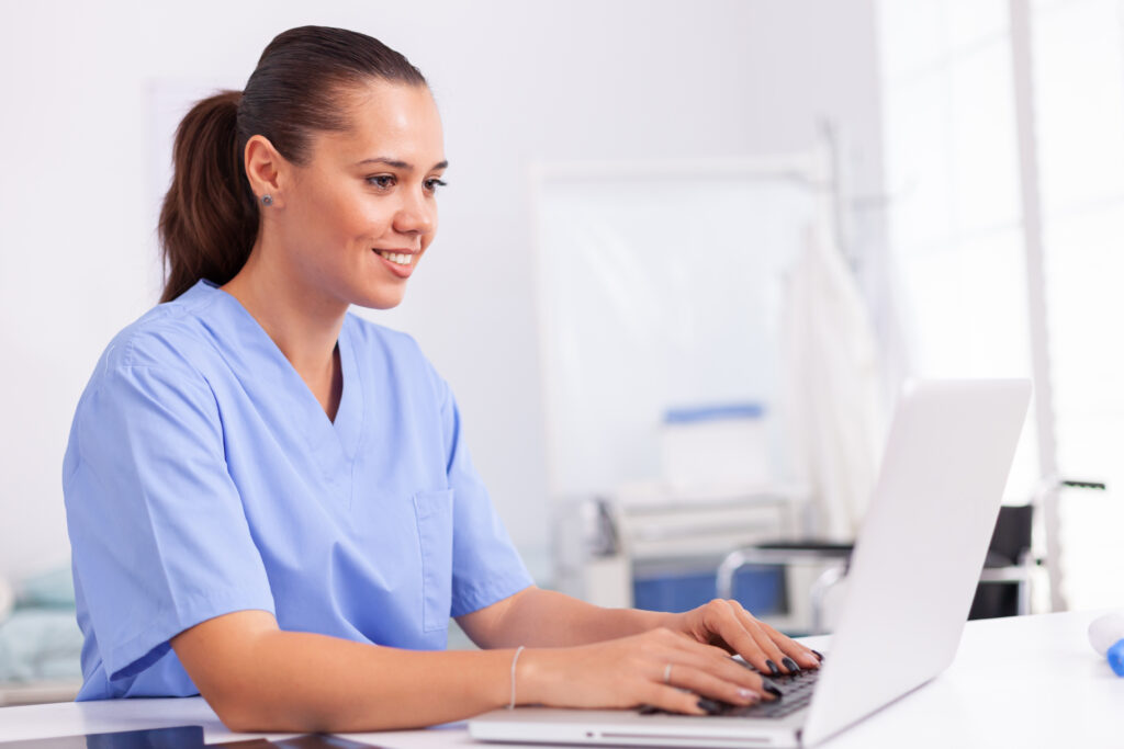Licensed Vocational Nurse putting data into a laptop